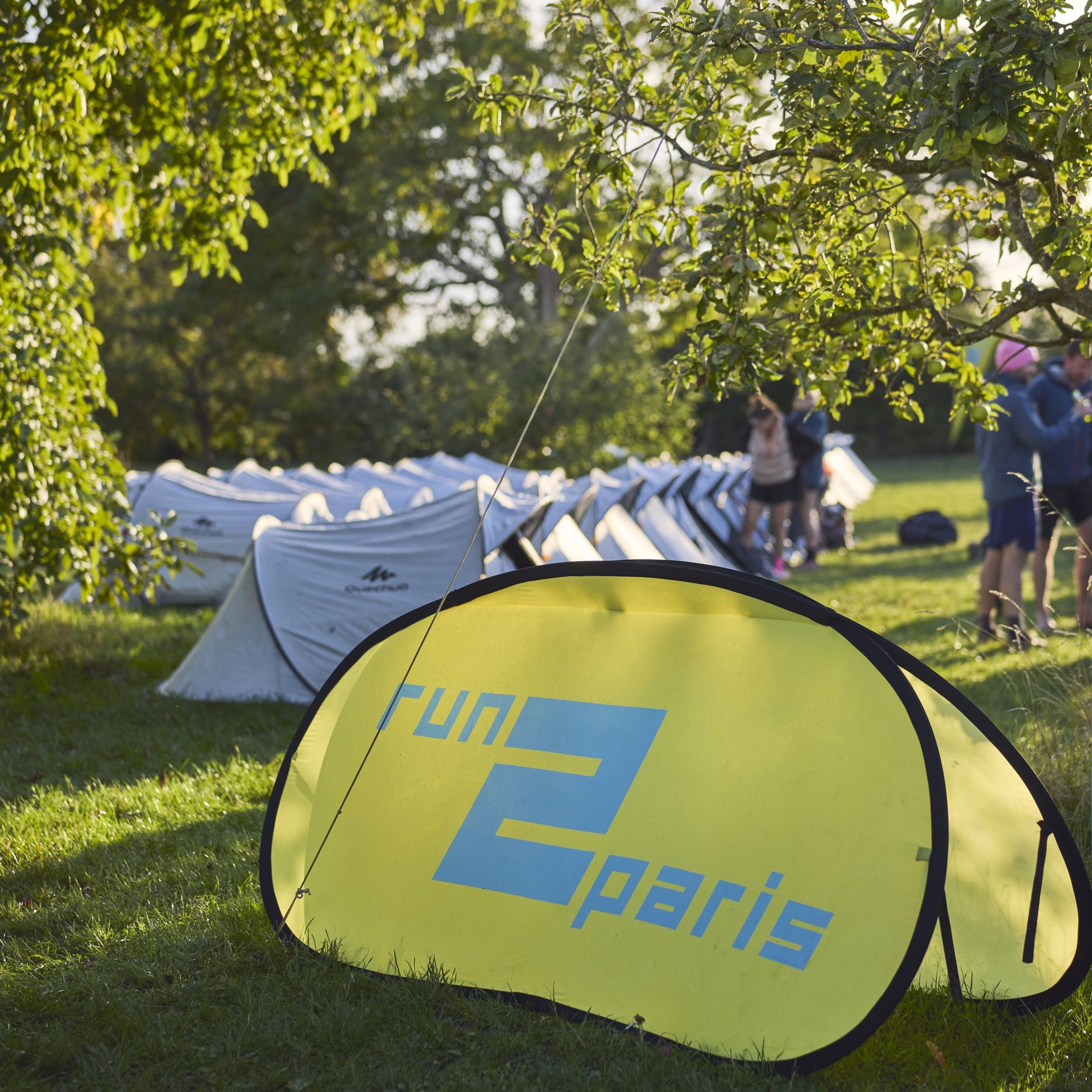 Bright yellow Run2Paris flag outdoors in a park during relay run event from London to Paris.