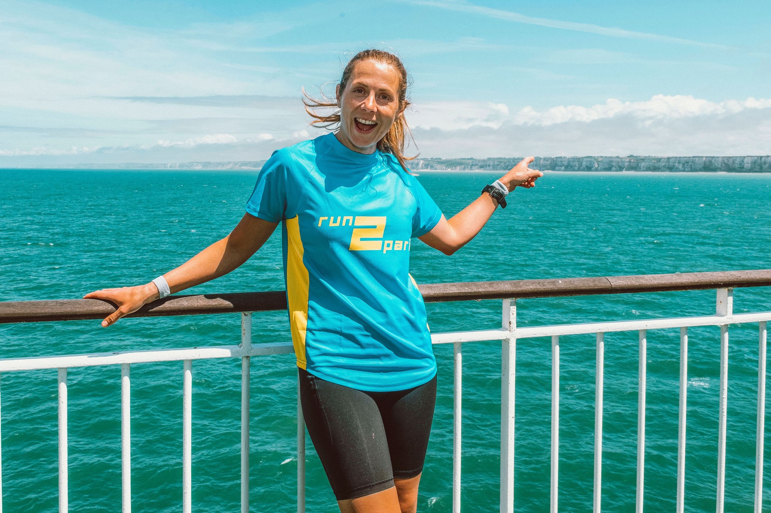 Vibrant female runner pointing at the coast during the Run2Paris relay, celebrating her achievement.