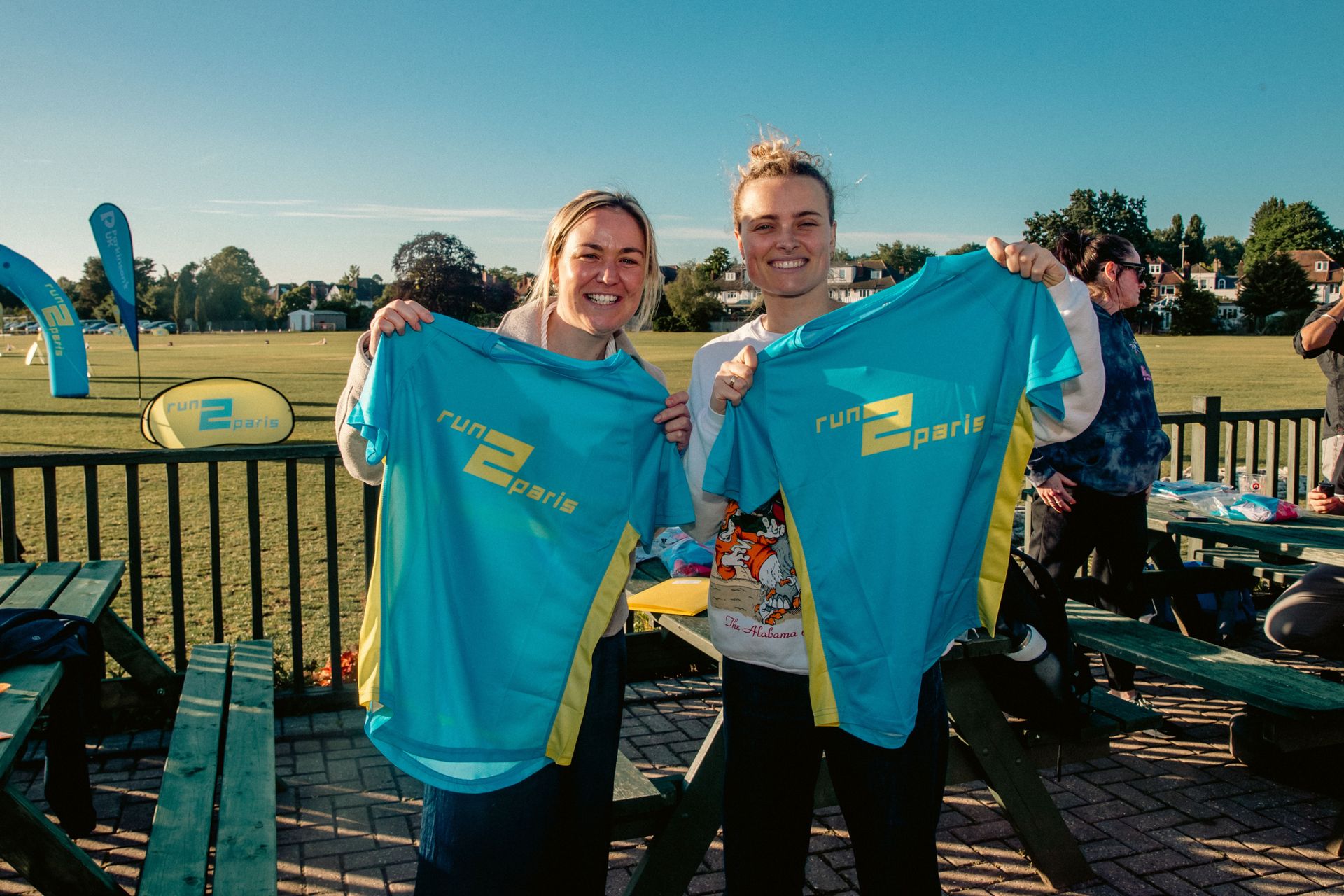 Bright smiling runners holding Run2Paris relay shirts after completing part of the London to Paris marathon relay.