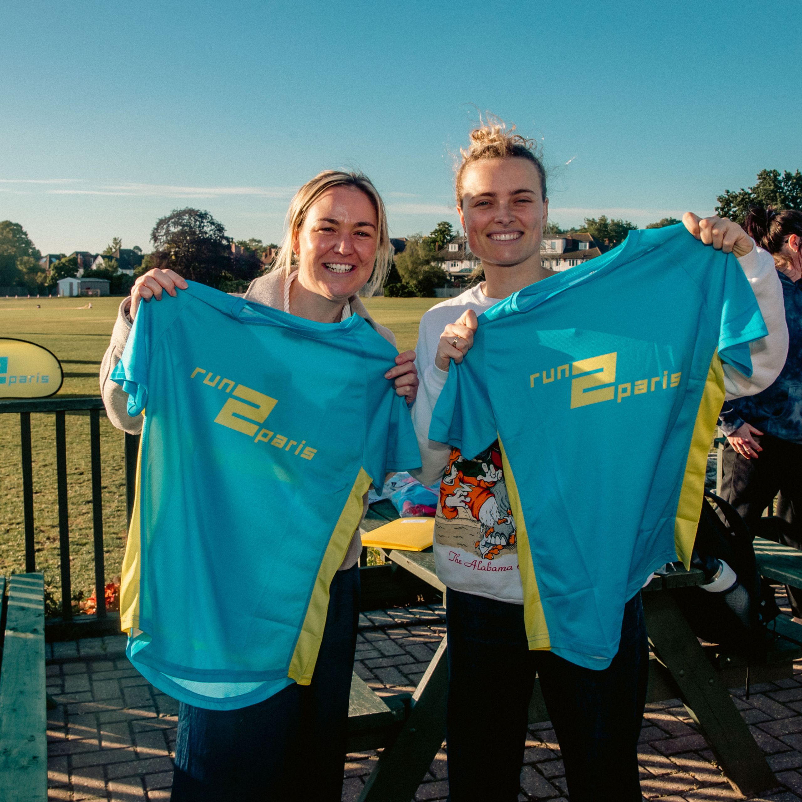 Bright smiling runners holding Run2Paris relay shirts after completing part of the London to Paris marathon relay.