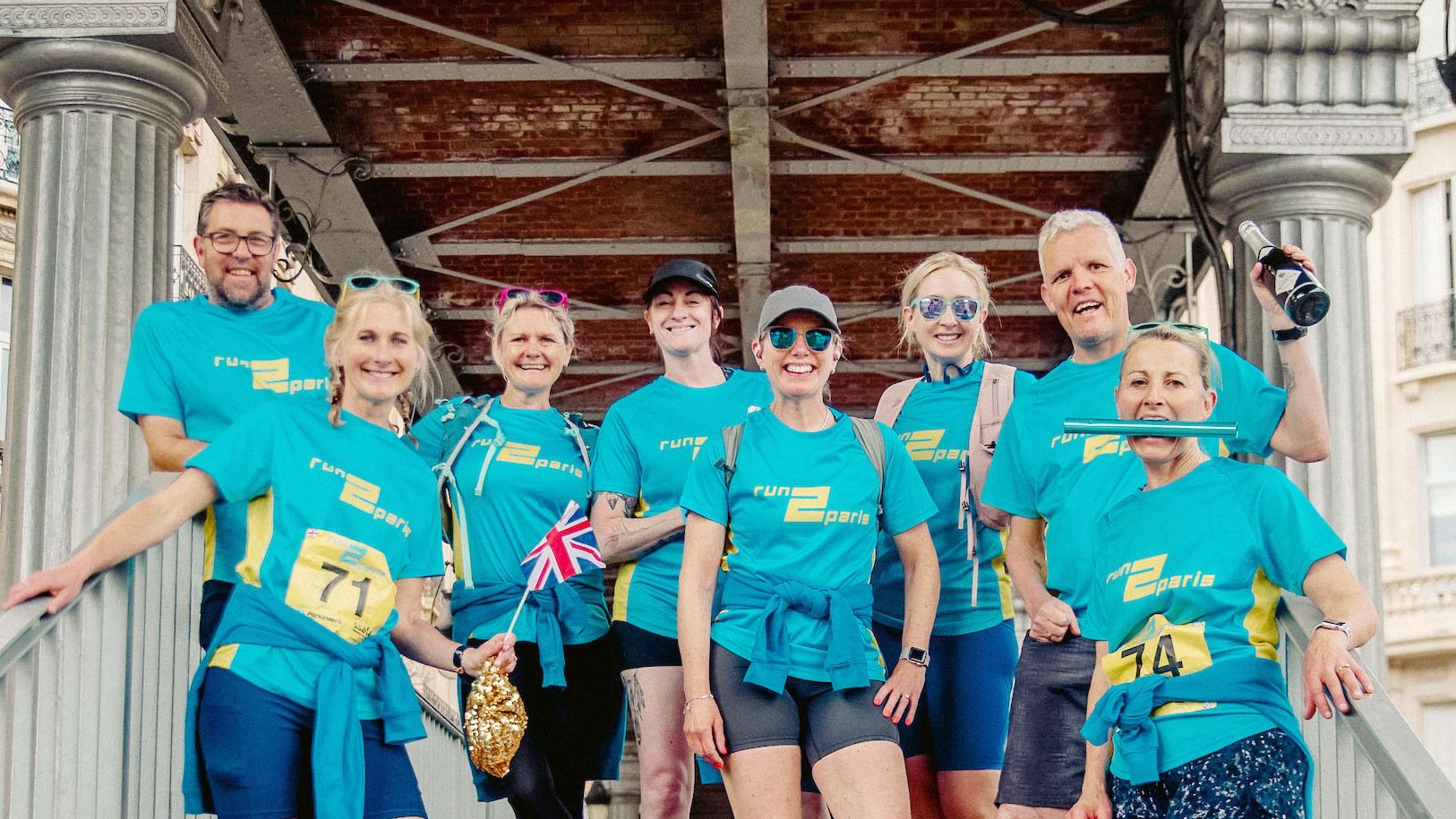 Running team in blue t-shirts celebrating after participating in the Run2Paris relay from London to Paris.