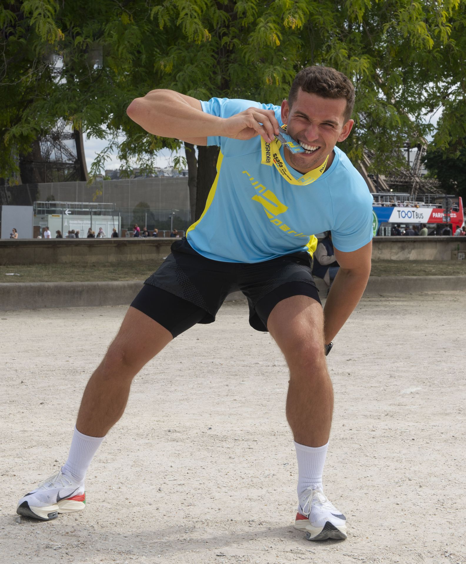 Medal-winning runner celebrating at Run2Paris relay event in London, smiling after completing his leg.