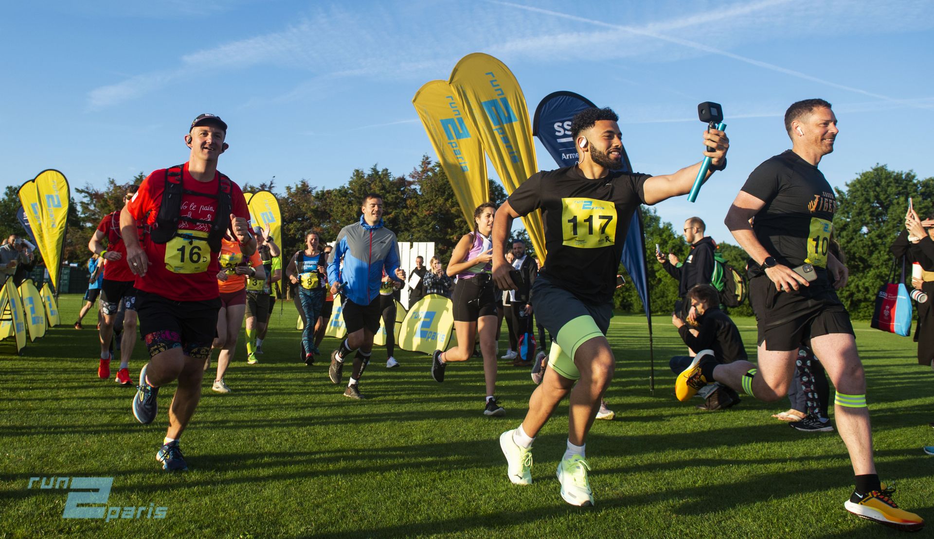 Vibrant group of runners participating in Run2Paris relay event on a sunny day.
