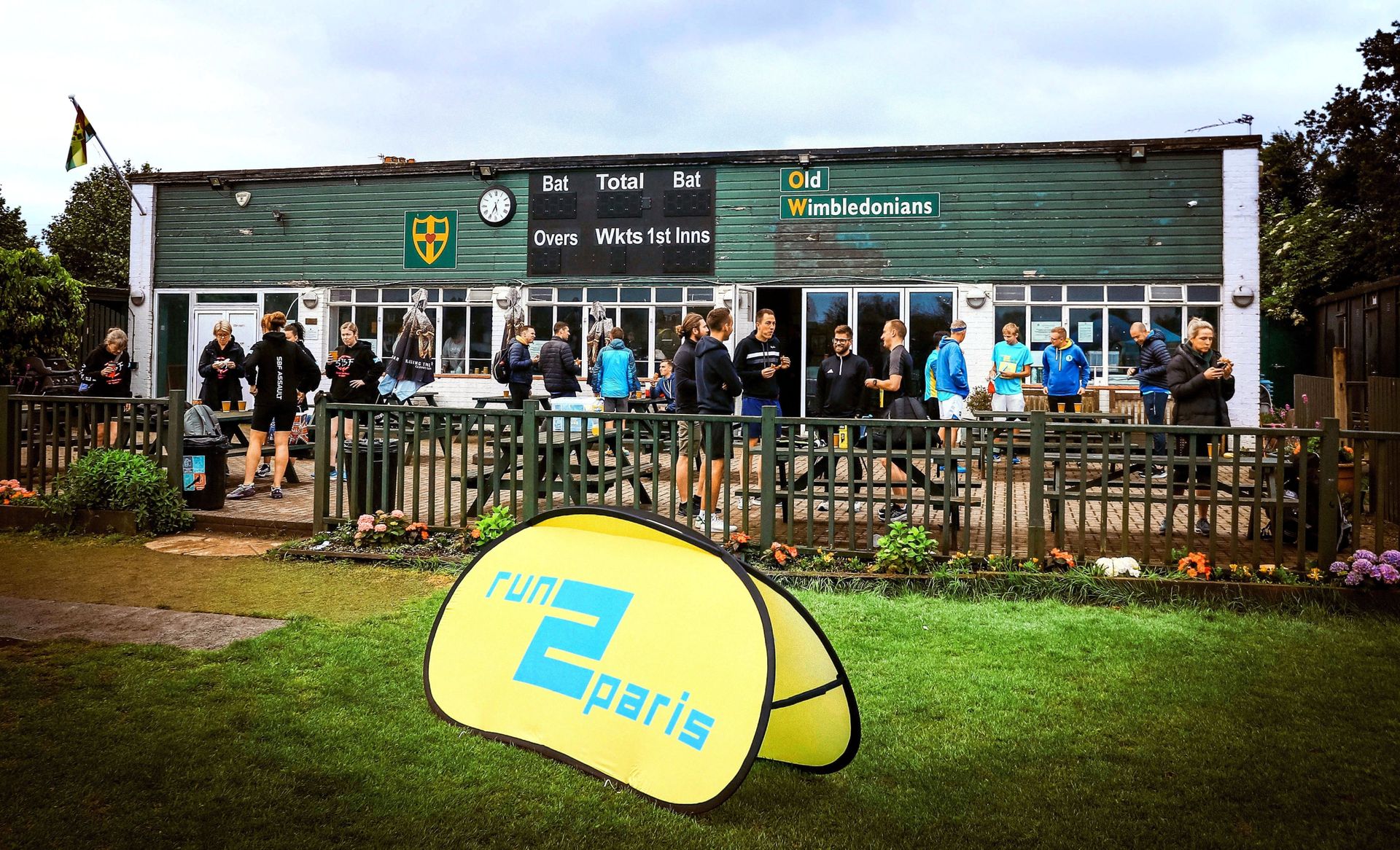 People gathering outside a sports clubhouse during the Run2Paris relay event from London to Paris.